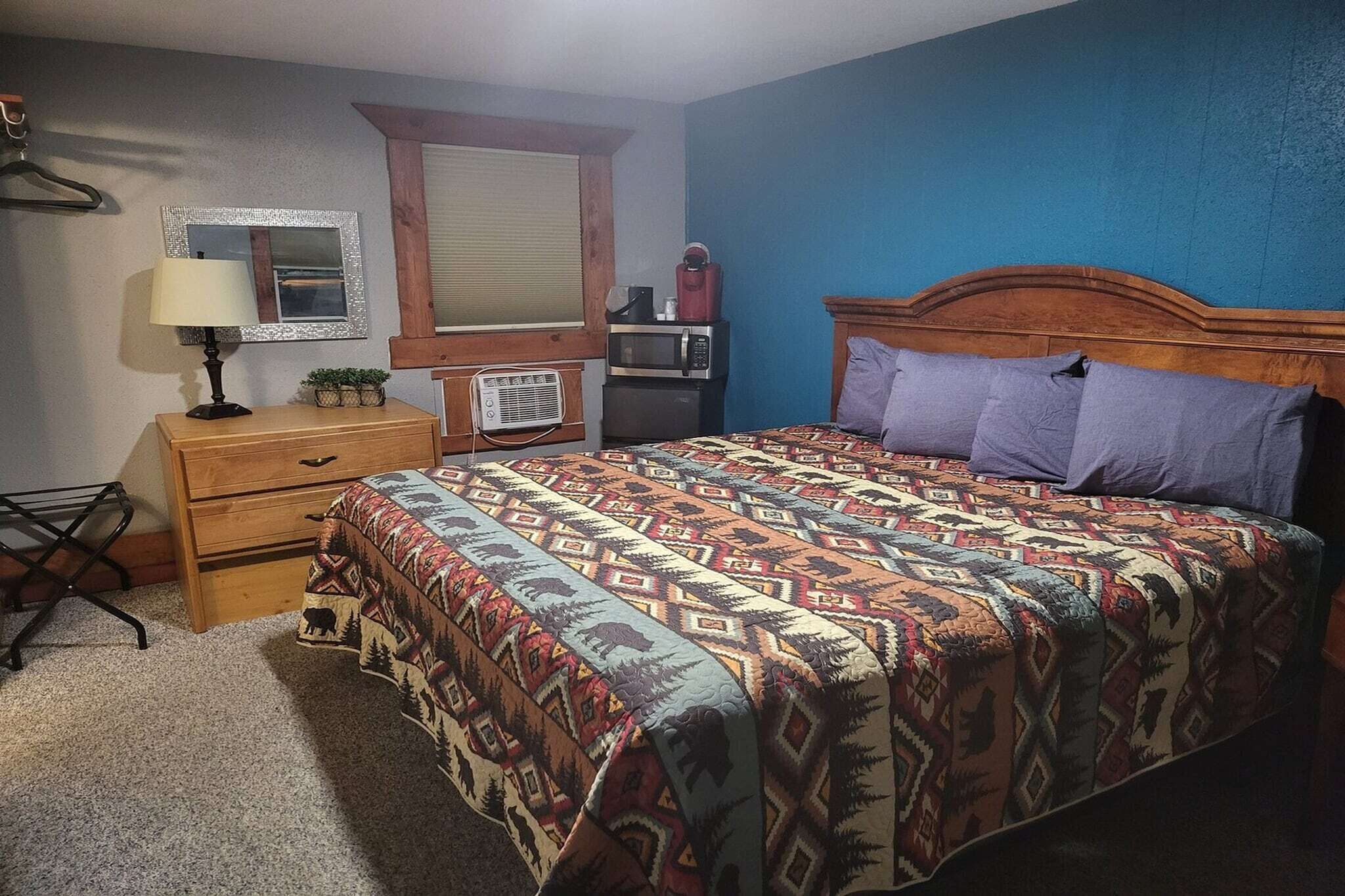 Een slaapkamer met een bed, een dressoir, een spiegel, een magnetron en een radio.