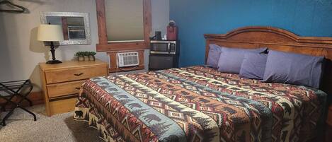Een slaapkamer met een bed, een dressoir, een spiegel, een magnetron en een radio.