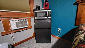Une petite cuisine équipée d’un four à micro-ondes, d’un petit réfrigérateur et d’un radiateur mobile.