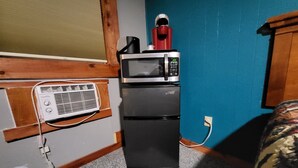 A compact kitchenette with a microwave, a small refrigerator, and a portable heater.