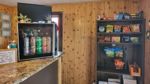 A counter with a beverage cooler, snack shelves, and a sign about a deposit system.