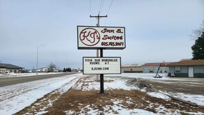 Une enseigne indiquant « KJ  ’s Inn & Suites », avec un numéro de téléphone et une adresse de site web permettant de consulter des photos des chambres rénovées.