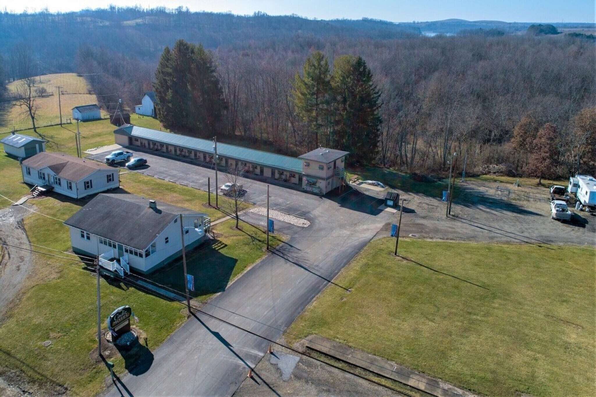 Un motel con un edificio central, aparcamiento y una casita.