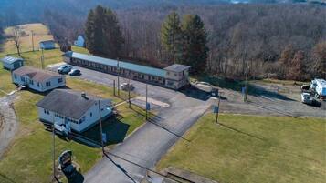 Un motel con un edificio central, aparcamiento y una casita.