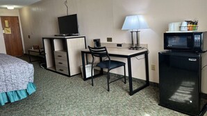 A hotel room with a bed, desk, chair, lamp, microwave, and a television. - Queen Bed Accessible Non-Smoking (Marysville, KS)