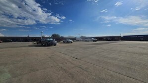 A parking lot with several cars, a building with a sign reading 'Landoll Lanes,' and a clear blue sky with clouds. - Queen Bed Accessible Non-Smoking (Marysville, KS)