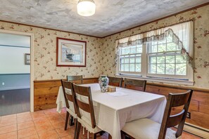 A dining room with a table set for four, wooden chairs, a vase, and a framed picture on the wall. - Classic Cape House 5M to Nauset Beach (Orleans)