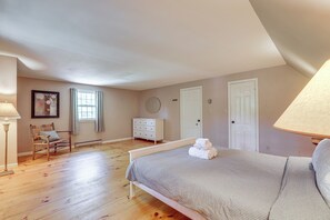 Un dormitorio con cama, cómoda, silla, ventana y lámpara.