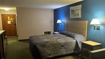 A hotel room with a bed, two bedside tables, a desk, a chair, and a door.