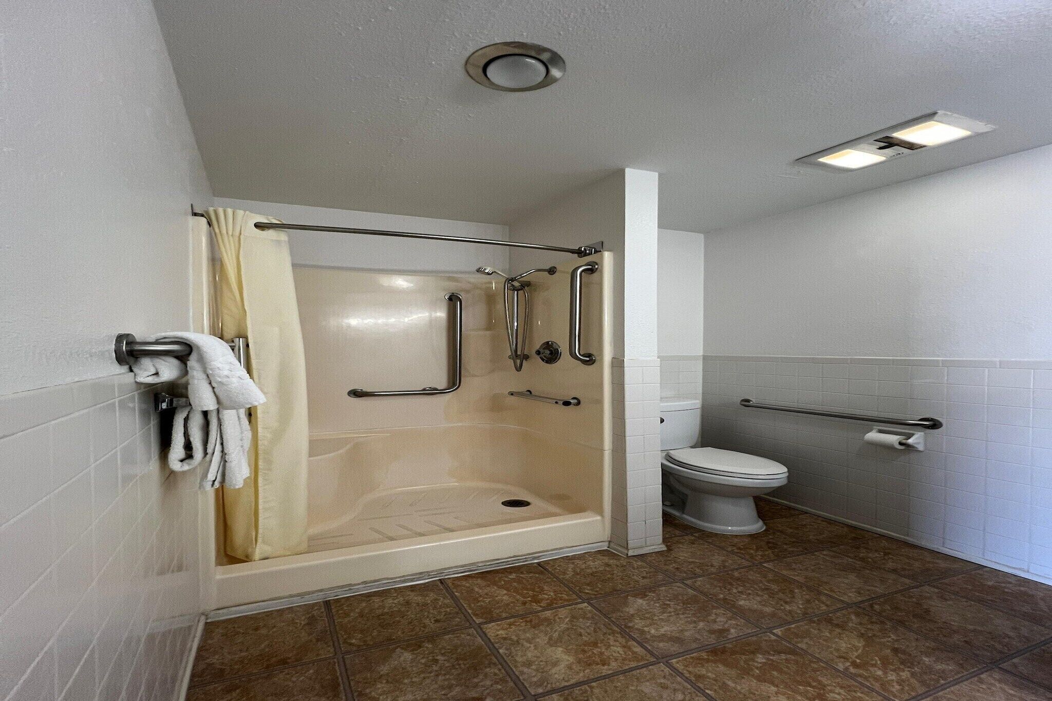 Une salle de bain équipée d’une douche, de toilettes et de barres d’appui.