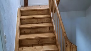 A wooden staircase with a handrail, leading to a higher floor.