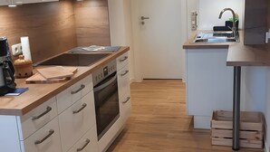 A modern kitchen with a built-in oven, a sink, and wooden flooring.