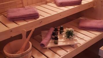 Un bain à remous en bois, agrémenté de serviettes violettes, d’un seau en bois et d’une petite plante.