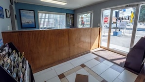 A reception area with a wooden counter, framed pictures on the wall, and a view of the street through large windows.