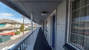 A corridor with a metal railing, a blue door, and a window on the right.