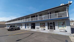 A motel with a two-story structure, a balcony on the second floor, and a parking lot with a single vehicle.