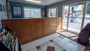 A reception area with a wooden counter, framed pictures on the wall, and a view of the street through large windows.