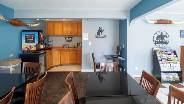 A dining area with a glass table, wooden chairs, a coffee machine, and a menu display.