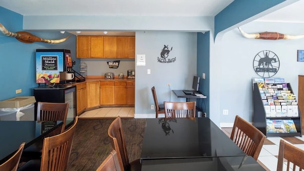 A dining area with a glass table, wooden chairs, a coffee machine, and a menu display. - Queen Bed Accessible Non-Smoking (Pendleton OR)