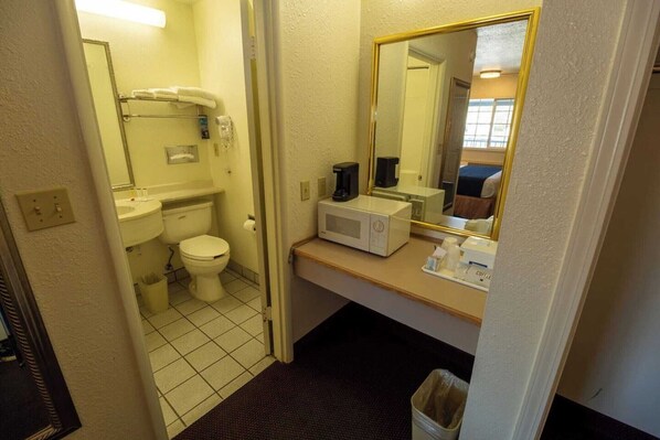 A small bathroom with a toilet, sink, and a microwave on the counter.