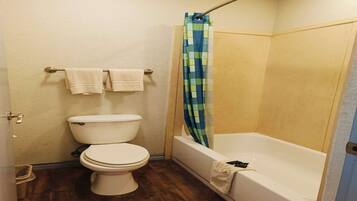 A bathroom with a toilet, a bathtub, and a shower curtain.