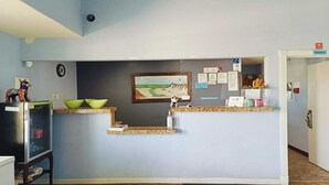 A reception desk with a framed painting, a clock, and various informational cards.