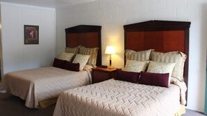 A hotel room with two single beds, a nightstand with a lamp, and a framed picture on the wall.