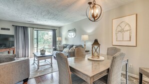 A living room with a dining table, chairs, a sofa, a television, and a chandelier. - Walk to Shore! Condo w/ Balconies in Myrtle Beach (Myrtle Beach)