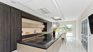 Una cocina moderna con una isla central, armarios oscuros y un amplio ventanal con vistas al exterior.