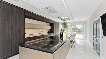 A modern kitchen with a central island, dark cabinetry, and a large window providing a view of the outdoors.