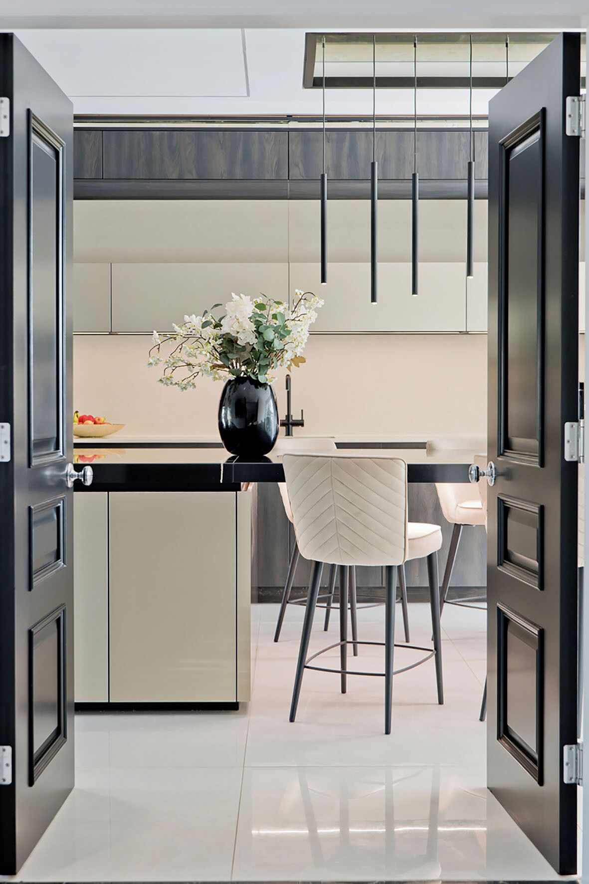 A modern kitchen with a central island, bar stools, and a vase of flowers.