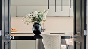 Una cocina moderna con una isla central, taburetes de bar y un jarrón con flores.
