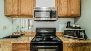 A kitchen with a stove, microwave, and cabinets.