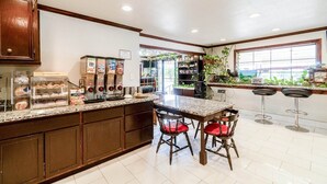 A kitchen with a granite countertop, a coffee machine, and a dining area with a table and chairs.