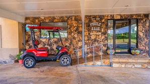 A building entrance with a stone facade, a red golf cart, and a sign reading 'Purple Sage Office.'