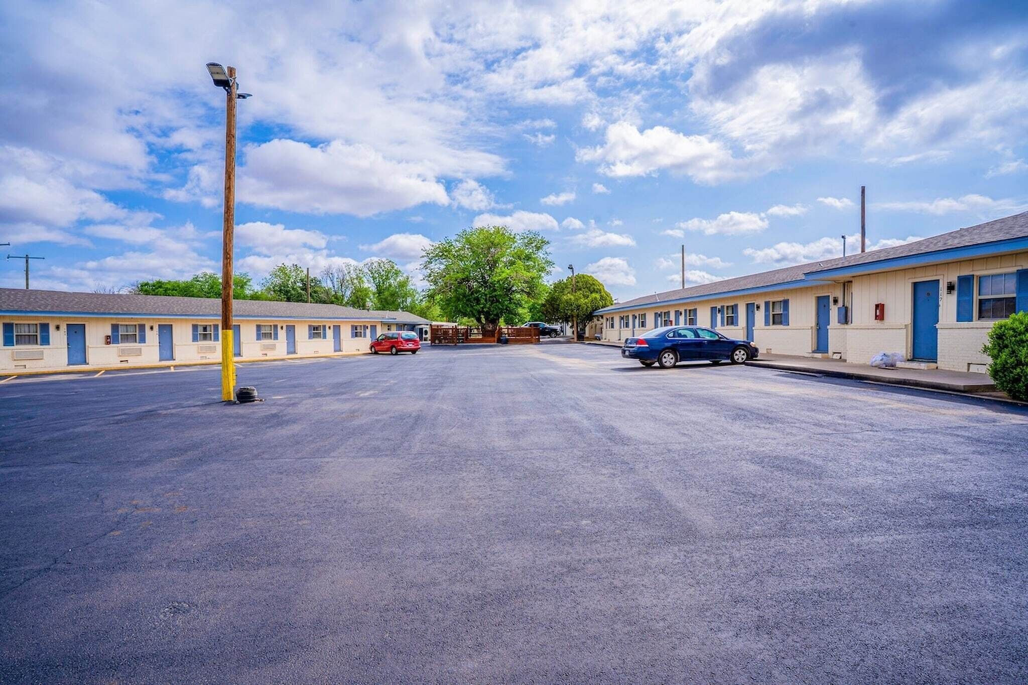 A motel with a parking lot, a street lamp, and two cars parked.