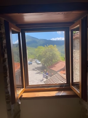 A room with a large window overlooking a mountainous landscape and a parking area.
