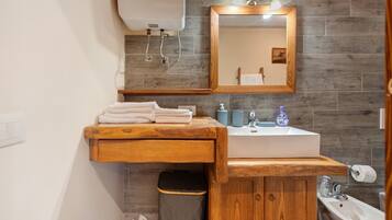 A bathroom with a wooden vanity, a sink, a mirror, and a toilet.