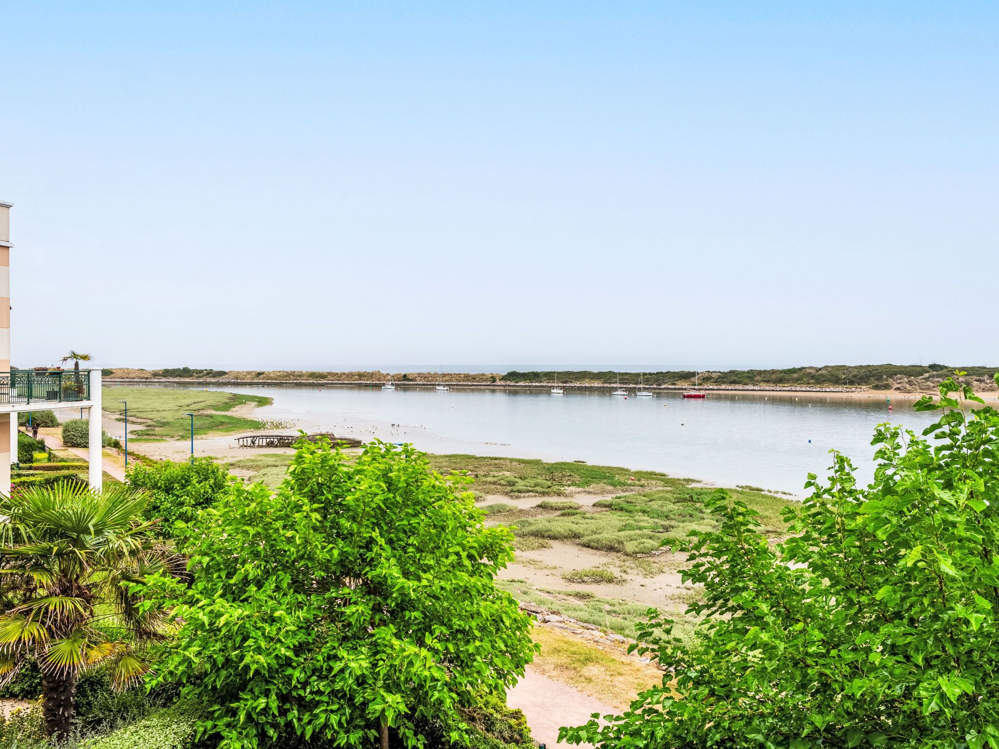 Une vue sur le fleuve, avec un pont, des bateaux et de la verdure.