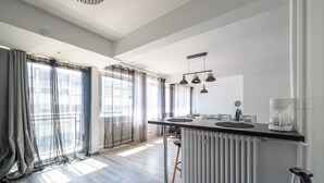 Una cucina moderna con isola centrale, illuminazione a sospensione e vista sulla città tramite ampie finestre.