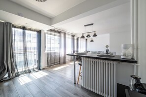 Eine moderne Küche mit einer zentralen Kochinsel, Pendelleuchten und Blick auf die Stadt durch große Fenster.