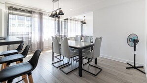 Zona pranzo moderna con tavolo rettangolare, sei sedie e una ventola da pavimento.
