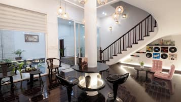 Un intérieur moderne avec une table ronde, des tabourets de bar, un escalier et un mur décoré de disques vinyles.