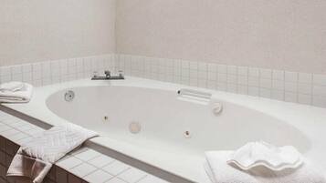 A white bathtub with a control panel, a towel on the side, and a tiled wall.