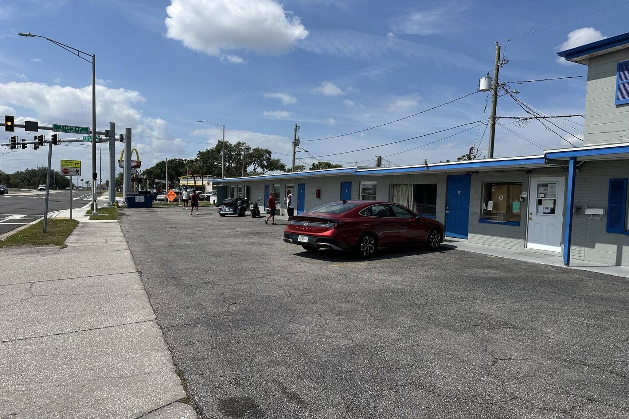Un motel comprenant plusieurs chambres, un parking et situé à un carrefour.