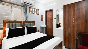A bedroom with a bed, a wardrobe, a bedside table, a mirror, and an air conditioning unit. - Super Hotel O Gachibowli Near ISB (Hyderabad)