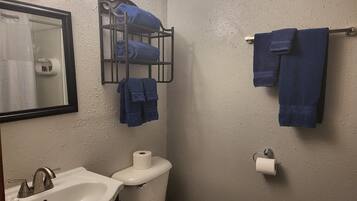 Un baño con lavamanos, inodoro y toallero con toallas.