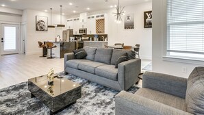 Una sala de estar moderna con un sofá gris, una mesa de centro negra y un sillón gris.