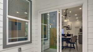 Una habitación con puerta corrediza de vidrio que da a un comedor, una lámpara de techo y una puerta con picaporte.