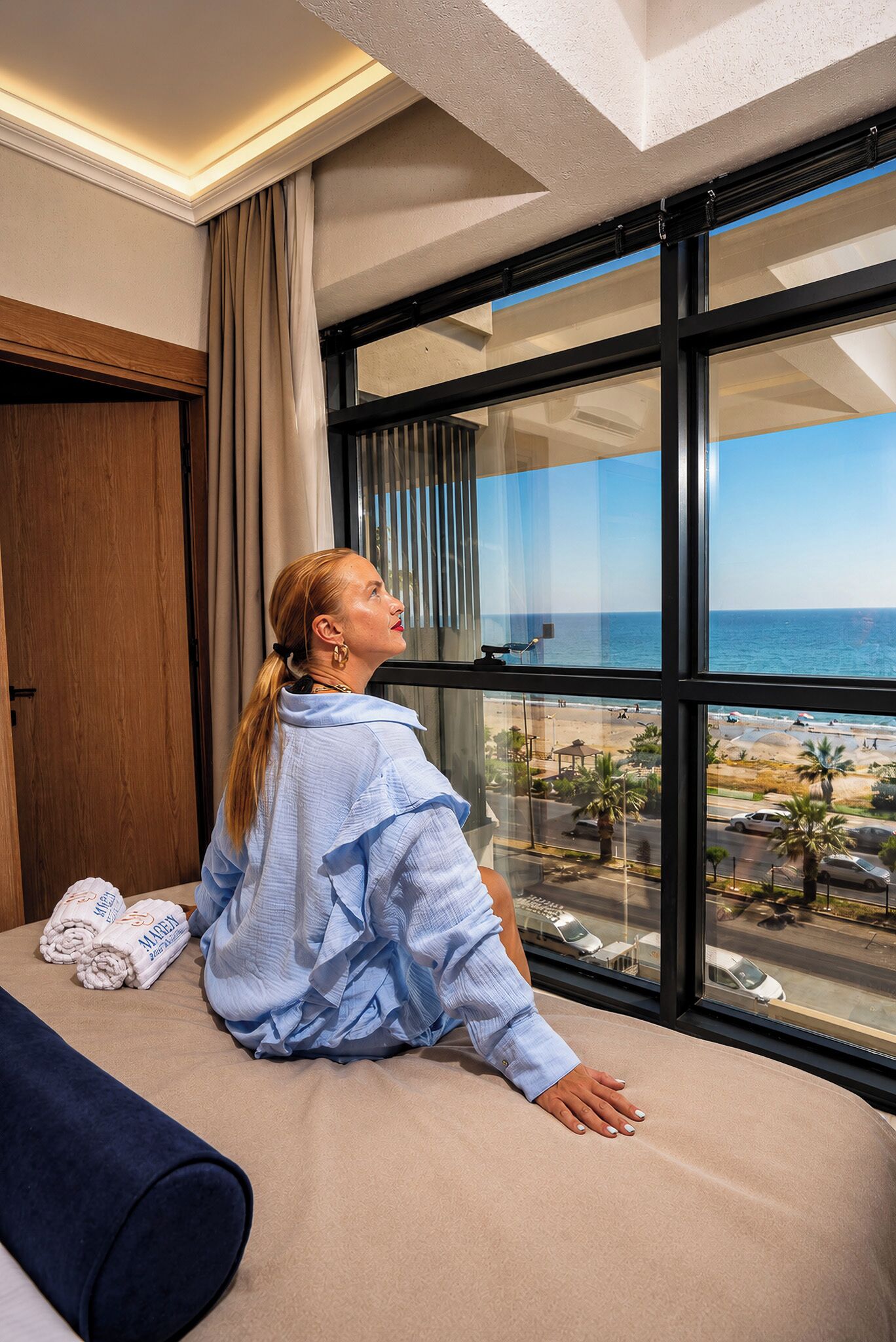 Eine Person sitzt am Fenster mit Blick auf den Strand.